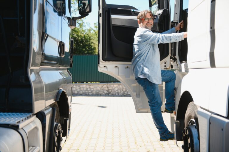 Portrait of bearded trucker standing by his truck vehicle. Transportation service. Truck driver job.